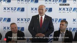Netanyahu stands between two seated men while speaking into a microphone