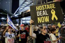 Anti-government protesters demonstrate for the release of hostages. Some are carrying the blue and white flag of Israel and one person is carrying a sign that reads, "HOSTAGE DEAL NOW"