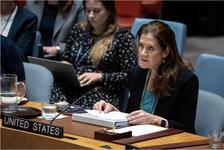 United States Ambassador to the United Nations Dorothy Shea sitting at a desk in a blue chair with her hands resting on a white piece of paper and white binder