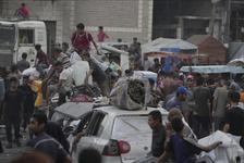 Displaced Palestinians climb over cars with their belongings on a crowded street