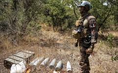 A French peacekeeper of the United Nations Interim Force in Lebanon (UNIFIL) stands by munitions laying on dry grass