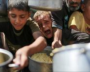 A child cries as he and others hold out pots to receive cooked food