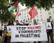 Protesters in London attend a vigil for journalists killed in Gaza. A banner reads, "Stop killing journalists in Palestine"