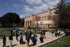 Students walk across campus at UCLA in front of a large brick building