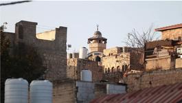 The sun shines against orange-beige concrete brick buildings