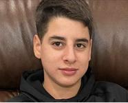 Mohammed Ibrahim wearing a black hoodie while sitting in a brown leather chair