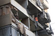 People stand on the balcony of a damaged building