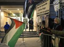 Protestors gather outside Park East Synagogue waving a Palestinian flag and holding a sign that reads: "Stop the Genocide. Lift the Siege. End the Whole Occupation."