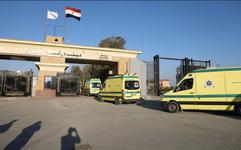Yellow vans, labeled as Egyptian Ambulances, wait at a border crossing station.