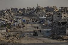 People walk down a dirt road surrounded by destruction
