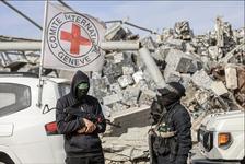 Two members of Hamas hold rifles and stand next to a vehicle flying an ICRC flag