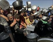 People crowd together while holding out pots to collect cooked food