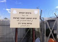 A sign written in Hebrew and Arabic stands in front of a barbed wire fence