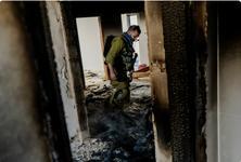 An Israeli soldier inspects the burnt interior of a house following the settler attack on the Tubasi family as they returned to the home they had been forced from