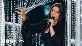 Yuval Raphael, representing Israel, sings into a microphone as she steps out from behind a crystal curtain