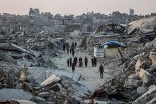 Palestinians walk amid the rubble of destroyed buildings
