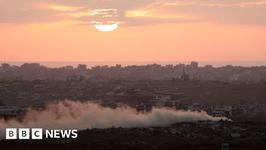 Smoke rises from Gaza as the sun sets over destroyed buildings
