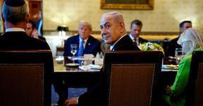 Netanyahu turns to look behind him while seated at a dining table across from Donald Trump